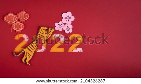 Chinese New Year. Decoration with traditional Chinese New Year motifs, cut out paper decorations on red cardboard background. Copy space. Royalty-Free Stock Photo #2104326287