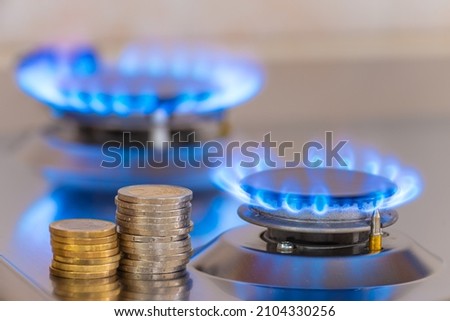 Gas stove lit, with stacks of coins above it. Increase in gas costs and tariffs.
 Royalty-Free Stock Photo #2104330256