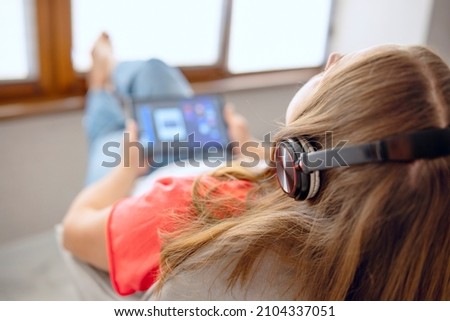 Close up back rear view calm young carefree woman enjoying lounge free lazy weekend time, listening to favorite music in headphones relaxing on armchair. Royalty-Free Stock Photo #2104337051