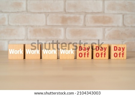 Wooden blocks with "Work" and "Day Off" text of concept. Royalty-Free Stock Photo #2104343003