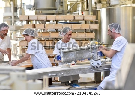 Worker in a large bakery - industrial production of bakery products on an assembly line 