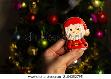 Cookies in the shape of santa claus.Close-up homemade gingerbread santa cookie. Christmas tree lights. Bokeh, blurred light background. Happy new year. Copy paste, text space. Background, cover photo.