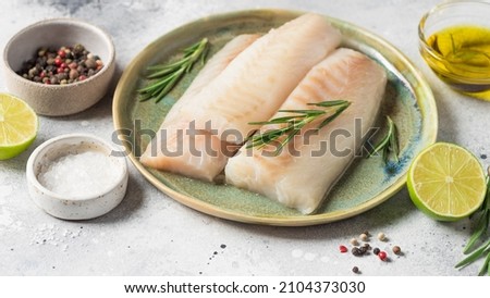 Raw fresh cod loin fillet steak with aromatic herbs, spices, lime and olive oil on gray background. Healthy food and diet concept. banner