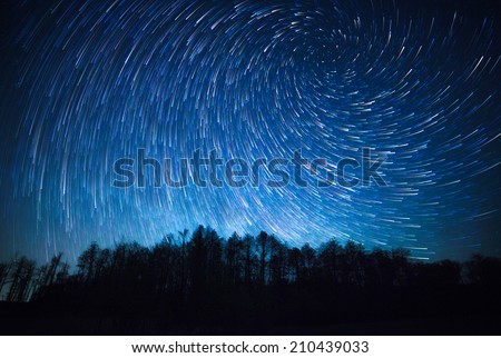 night sky, spiral star trails and the forest Royalty-Free Stock Photo #210439033
