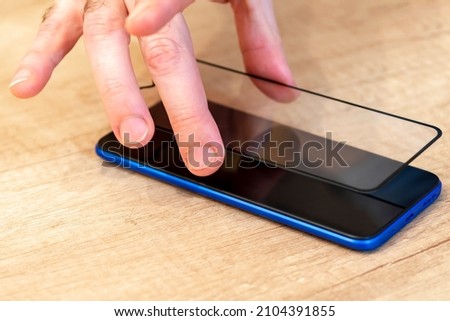 Smartphone protective glass. Hands, protective glass, phone. The concept of protecting the screen of a mobile phone, Applying protection to the screen of a gadget.