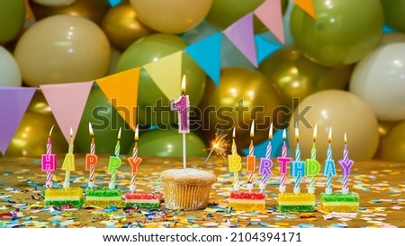 Cupcake with a candle one year old, Greeting colorful card happy birthday to a child 1 year old, birthday cupcake with candles and birthday decorations