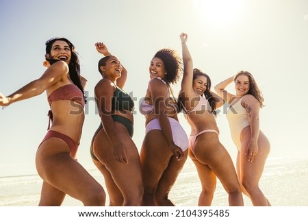 Shaking our summer bodies. Happy young women smiling cheerfully while dancing in swimwear. Carefree female friends having fun and enjoying their summer vacation at the beach.