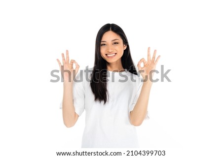 happy asian woman showing okay signs and looking at camera isolated on white