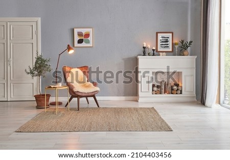 Modern room concept interior style, chair fireplace frame wicker carpet decoration, grey stone wall background. Royalty-Free Stock Photo #2104403456