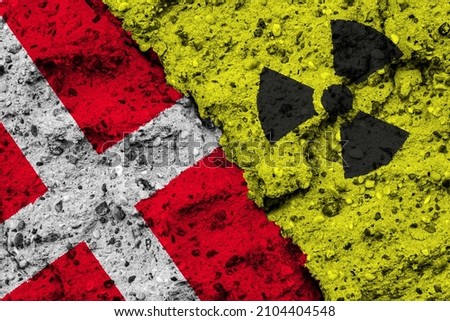 Concept of the Nuclear Energy Policy of Denmark with a flag and a radiation hazard sign painted on a rough wall