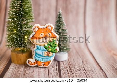The tiger is the symbol of the year 2022 on a wooden background with a herringbone and a place for text. Tiger 2022. Place for text on a wooden background. Gingerbread tiger.