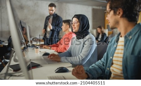 Female Muslim Student Wearing Hijab, Studying in Modern University with Diverse Multiethnic Classmates. She Asks Scholar a Question in College Room. Lecturer Shares Knowledge with Smart Scholars. Royalty-Free Stock Photo #2104405511