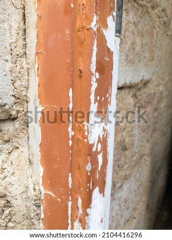 close up of old wood frame with dried paint peeling off placed against a brick wall