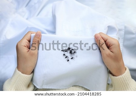 Hand showing dirty black ink stain on white shirt from unexpected accident. daily life stain concept. Royalty-Free Stock Photo #2104418285