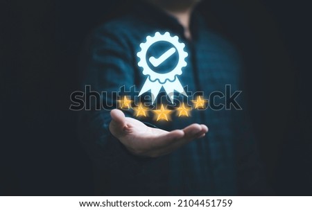 Businessman holding and showing the best quality assurance with golden five stars for guarantee product and ISO service concept. Royalty-Free Stock Photo #2104451759