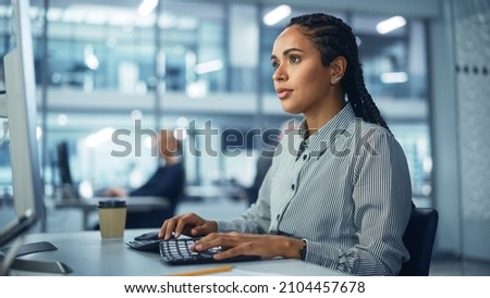 Corporate Office: Black Female IT Technician Using Desktop Computer, Uses Big Data Statistics, Graphs. Smiling Creative Software Engineer Work on eCommerce Project Marketing, Development. Royalty-Free Stock Photo #2104457678