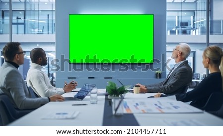 Office Conference Room Meeting using Video Call: Diverse Team of Successful Managers, Executives Talk, Use Green Screen Chroma Key TV. Businesspeople Work on Strategy for an e-Commerce Startup
