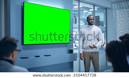 Office Conference Room Meeting Presentation: Charismatic Black Businessman Talks, Uses Green Screen Chroma Key Wall TV. Successfully Presenting a e-Commerce Product to Group of Multi-Ethnic Investors