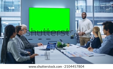 Office Conference Room Meeting Presentation: Charismatic Black Businessman Talks, Uses Green Screen Chroma Key Wall TV. Successfully Presenting a e-Commerce Product to Group of Multi-Ethnic Investors