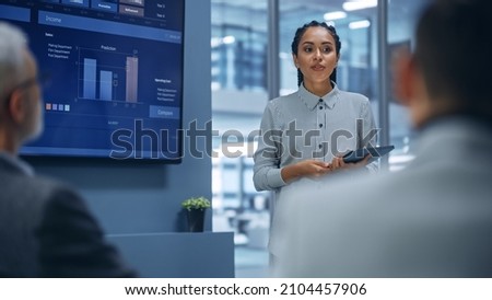 Diverse Office Product Presentation: Successful Black Female Digital Entrepreneur Uses TV Screen with Big Data, Statistics, Talks about Company Growth, Discusses Strategy with Investors, Managers