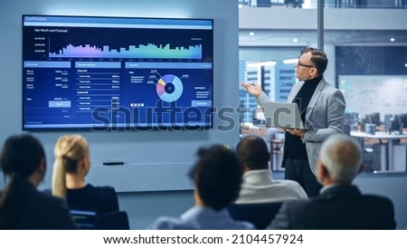 Modern Product Presentation Event: On-Stage Successful Caucasian Businessman Speaker Presents e-Commerce Startup Big Data Statistics, Charts, Revenue Growth Infographics. Live Event. Press Conference