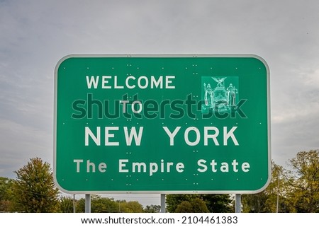 A Welcome to New York state line highway sign marking the border with the Commonwealth of Pennsylvania.