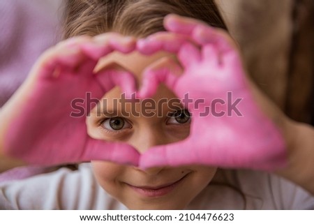Child's painted hands with pink color shows heart. Valentines day card. 