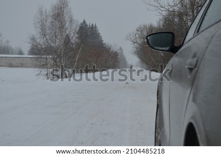 A car on a snow-covered road along the forest