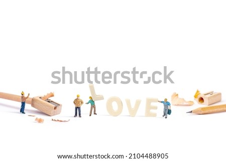 selective focus of miniature worker holding wood text love on white background.