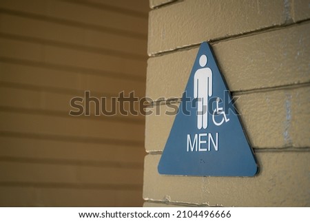Blue Triangle Men’s Public Bathroom sign on Brown Brick Wall
