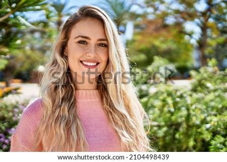 Young blonde woman smiling at the park Royalty-Free Stock Photo #2104498439