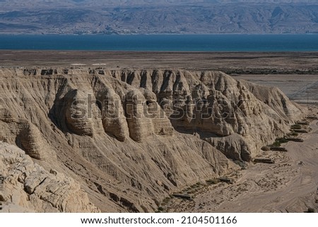 View of Wadi Qumran and the Dead Sea in the background as seen from the trail high above the canyon, located on the northwestern shore of the Dead Sea, Qumran National Park, Israel. Royalty-Free Stock Photo #2104501166