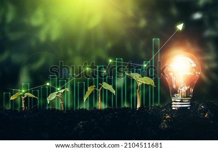 Light bulb is located on the soil, and plant are growing with growth graph.Renewable energy generation is essential in the future. Alternative sources of energy.Green energy development. Royalty-Free Stock Photo #2104511681