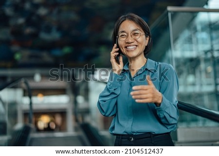 Surprised asian woman, hearing from an old friend, on the phone Royalty-Free Stock Photo #2104512437