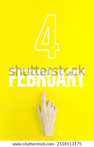 February 4th. Day 4 of month, Calendar date.Hand finger pointing at a calendar date on yellow background.Winter month, day of the year concept