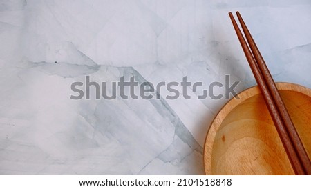 Wooden kitchenware that gives a classic and minimalist impression. Food and drink concept. Food Photography. Flat Lay, Wooden Chopsticks and bowl on the table. Space for text. Blue Pattern Background.