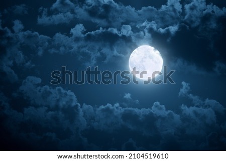 Dramatic photo illustration of a nighttime sky with brightly lit clouds and large, bright full moon would make a great background. Royalty-Free Stock Photo #2104519610