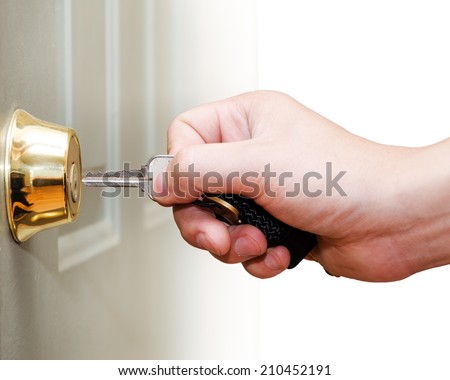 Photo of male hand putting house key into front door lock of house