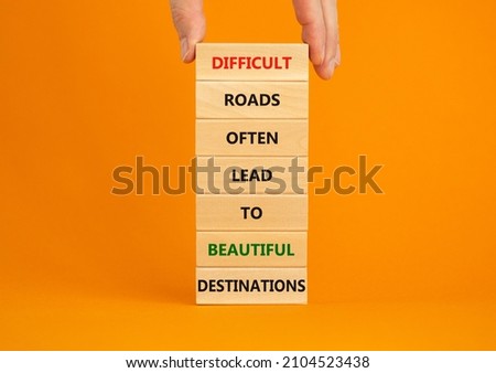Motivational symbol. Blocks with words Difficult roads often lead to beautiful destinations. Beautiful orange background, copy space. Businessman hand. Business, psychology and motivational concept.