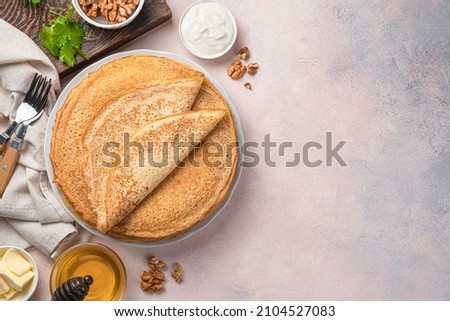 Traditional Russian blini on a light background with sour cream, honey and nuts. Maslenitsa. Homemade pancakes. Top view, copy space.