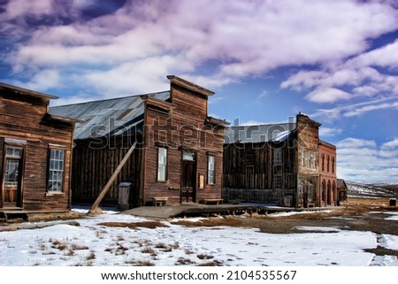abandoned western miner town in snowy winter.  Rustic old wood buildings cloudy sky 