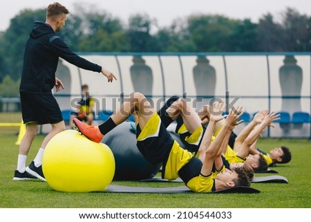 Soccer Players: Stretching Session With Physiotherapist. Youth Sports Team On Recovery Session After League Match. Football Players Warming Up on Grass Stadium Field Royalty-Free Stock Photo #2104544033