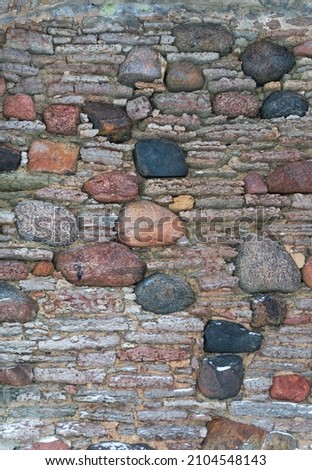 Detail of an ancient medieval wall of Toolse Order Castle built 1471. Layers of sedimental limestone blocks mixed with granite erratic boulders. Decorative masonry work. Estonia, North coast. Royalty-Free Stock Photo #2104548143
