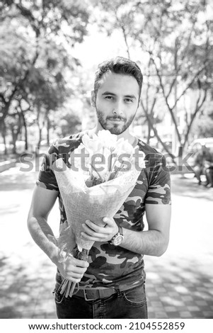 Young man handing flowers pink tulips to his girlfriend in the park.