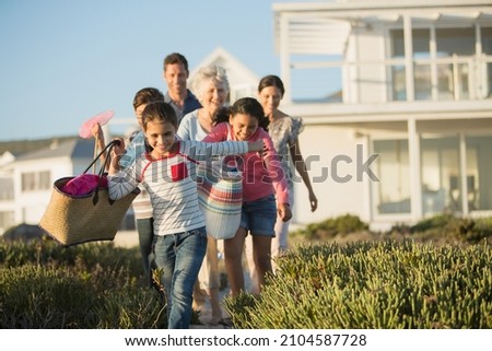 Family walking on beach path outside house Royalty-Free Stock Photo #2104587728