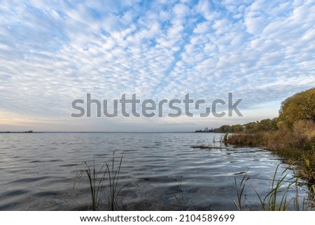 Colorful sunrise on the shores of Lake Nero. Autumn landscape with a lake in the early morning. A bright streak of light on the horizon, dawn.