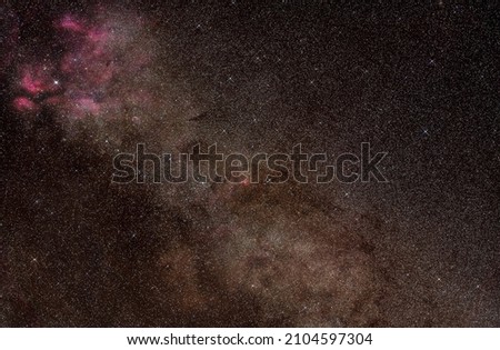 Night sky, many stars with milky way around Cygnus constellation, Red purple nebulosity around Sadr star visible. Long exposure stacked photo 