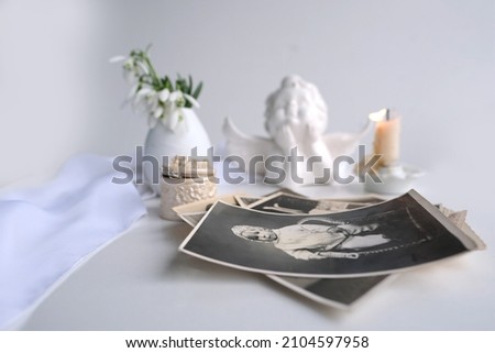 stack of vintage photos, baby photography of 1960, candle is lit, first spring flowers, snowdrop, Galanthus in vase, concept of family tree, genealogy, childhood memories