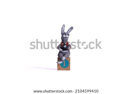 A hare with a camera made of paper and glue sits on a wooden cube of the perpetual calendar, on which the number "one" is written (isolated on a white background)