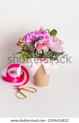 Delicate floral arrangement in paper cup. Gift for Woman's Day or Valentine's Day. Pink roses and chrysanthemums Royalty-Free Stock Photo #2104616822